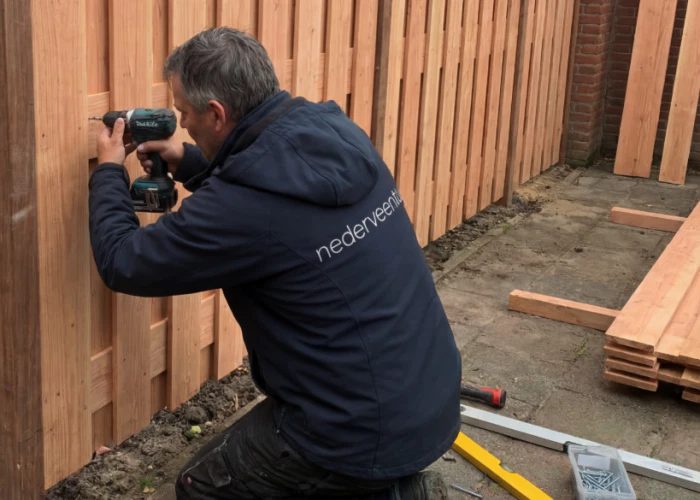 Werknemer van Nederveen Tuinen die een schutting aan het plaatsen is